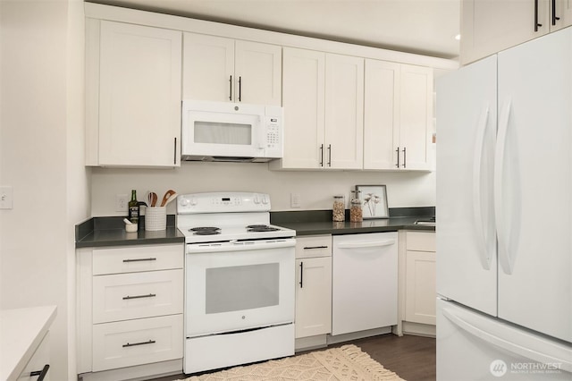 kitchen with dark countertops, white appliances, white cabinetry, and dark wood-type flooring