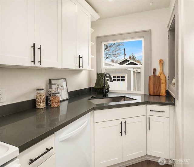 kitchen with dishwasher, dark countertops, white cabinets, and a sink