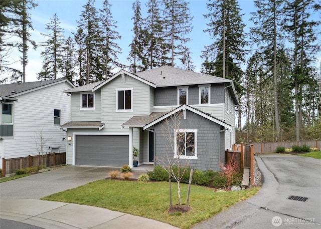 traditional home with driveway, roof with shingles, an attached garage, fence, and a front yard