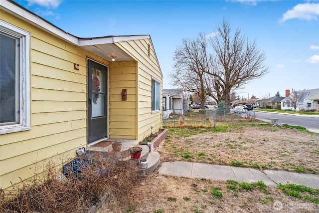 view of exterior entry featuring a residential view and fence