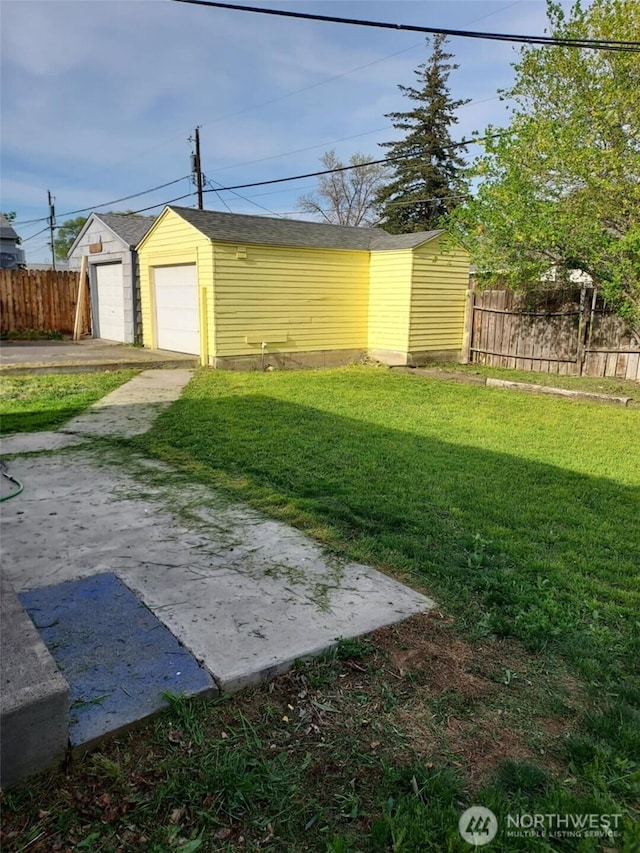 view of yard featuring a detached garage, fence, and an outdoor structure
