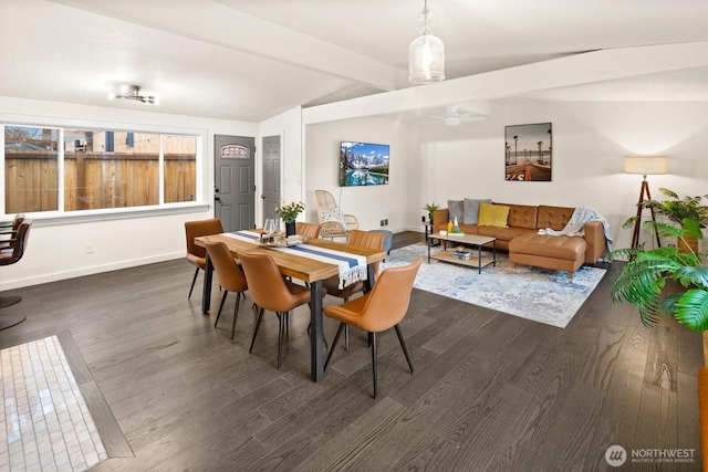 dining room with lofted ceiling with beams, dark wood finished floors, and baseboards