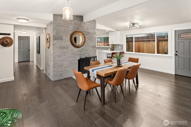 dining room with dark wood finished floors, lofted ceiling with beams, and baseboards