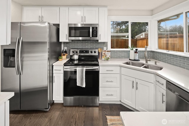 kitchen with appliances with stainless steel finishes, white cabinets, light countertops, and a sink