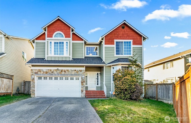 view of front of house featuring a garage, concrete driveway, stone siding, fence, and a front yard