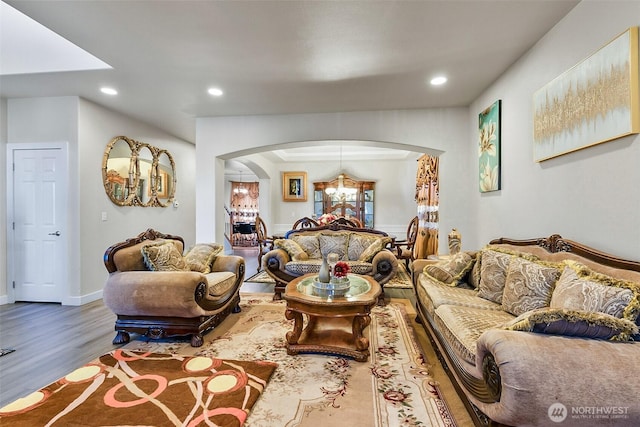 living area featuring a notable chandelier, arched walkways, wood finished floors, and recessed lighting