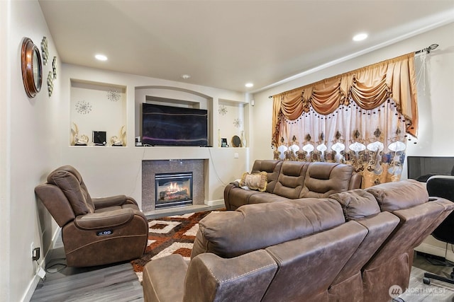 living room with a high end fireplace, baseboards, recessed lighting, and wood finished floors