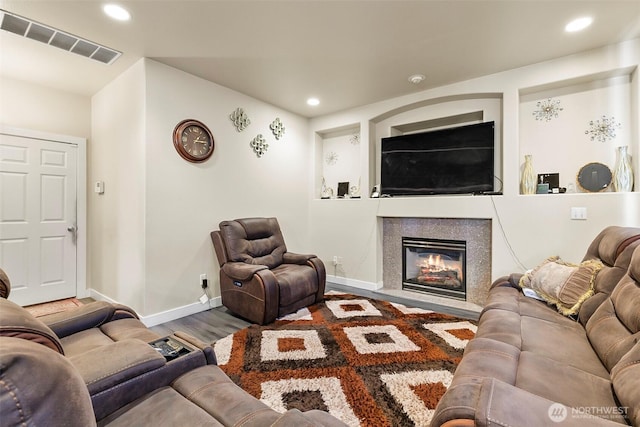 living area with baseboards, visible vents, a glass covered fireplace, wood finished floors, and recessed lighting