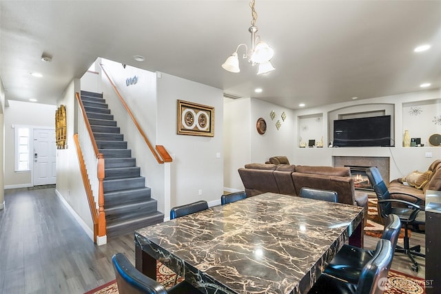 dining area featuring baseboards, stairway, dark wood-style flooring, and a glass covered fireplace