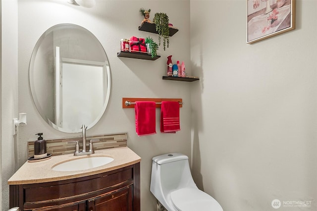 half bath featuring toilet, vanity, and decorative backsplash