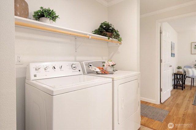 washroom featuring light wood finished floors, laundry area, baseboards, independent washer and dryer, and crown molding