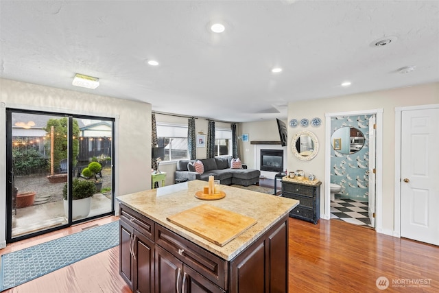 kitchen with a wealth of natural light, wood finished floors, a glass covered fireplace, and recessed lighting