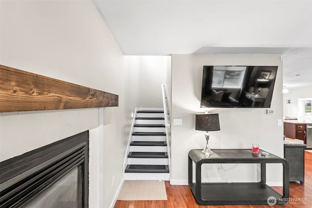 stairs with wood finished floors, a fireplace, and baseboards