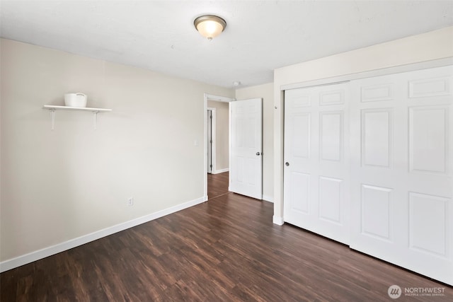 unfurnished bedroom with a closet, dark wood finished floors, and baseboards