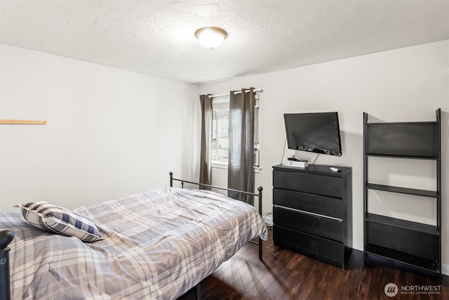 bedroom with dark wood finished floors, baseboards, and a textured ceiling