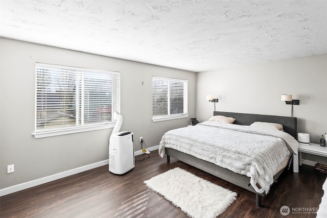 bedroom featuring baseboards, a textured ceiling, and wood finished floors