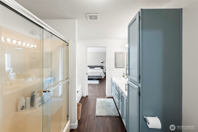 ensuite bathroom with visible vents, a shower stall, vanity, wood finished floors, and ensuite bath