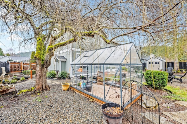 rear view of house featuring an outbuilding, a greenhouse, and fence