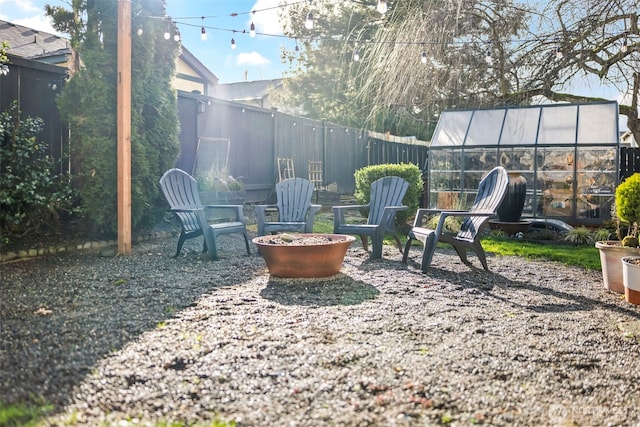 view of yard featuring a fire pit, an outbuilding, fence, and an exterior structure