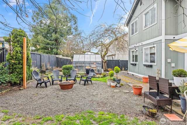 view of yard with an exterior structure, a patio area, an outdoor fire pit, a fenced backyard, and an outbuilding