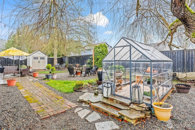 view of yard with a patio, an outbuilding, an outdoor fire pit, a fenced backyard, and a greenhouse