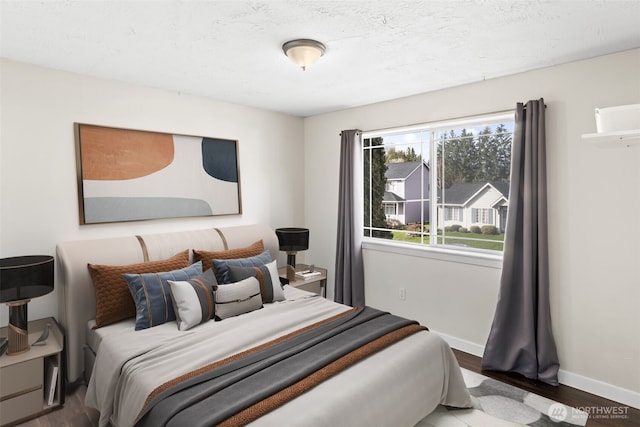 bedroom with a textured ceiling, baseboards, and wood finished floors