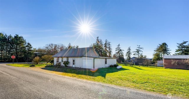 view of side of property featuring metal roof and a lawn