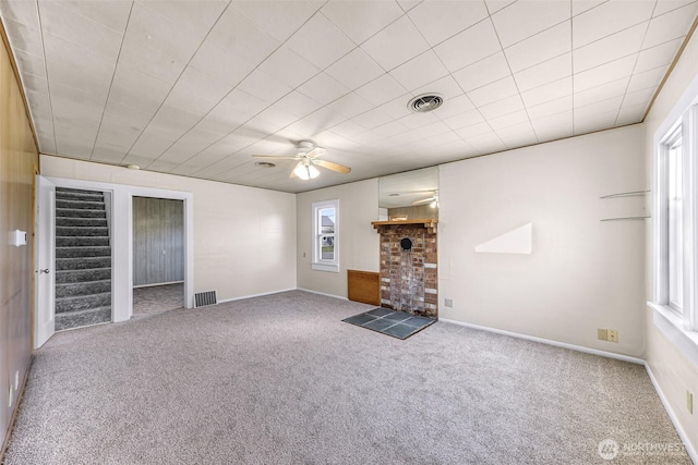 unfurnished living room with carpet, a healthy amount of sunlight, visible vents, and stairs