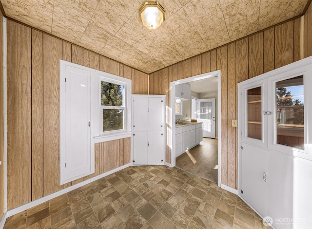 interior space featuring wood walls, an ornate ceiling, and baseboards