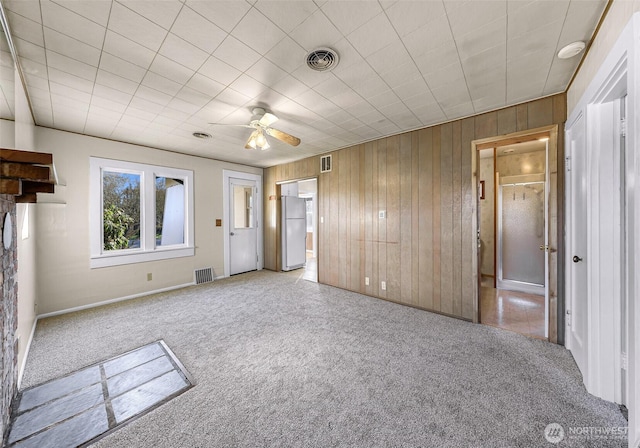 interior space with light carpet, wooden walls, and visible vents