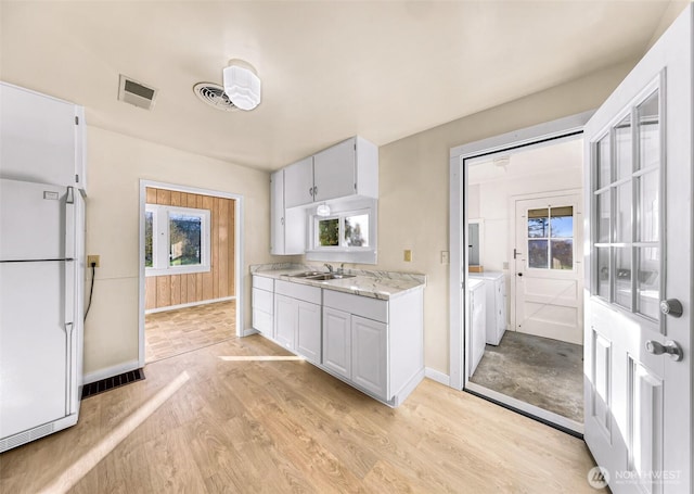 kitchen with freestanding refrigerator, light countertops, white cabinetry, separate washer and dryer, and a sink