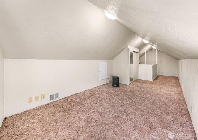 bonus room featuring carpet, visible vents, vaulted ceiling, and a textured ceiling