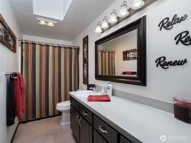 bathroom with toilet, a skylight, and vanity