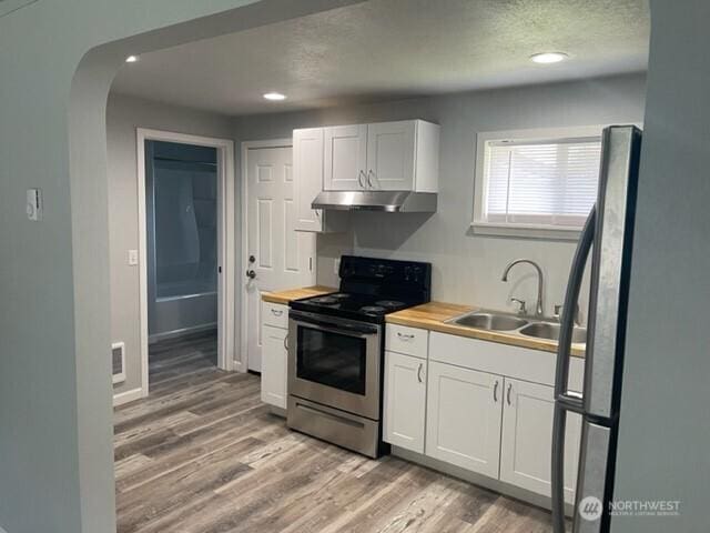 kitchen featuring under cabinet range hood, a sink, white cabinetry, wooden counters, and appliances with stainless steel finishes