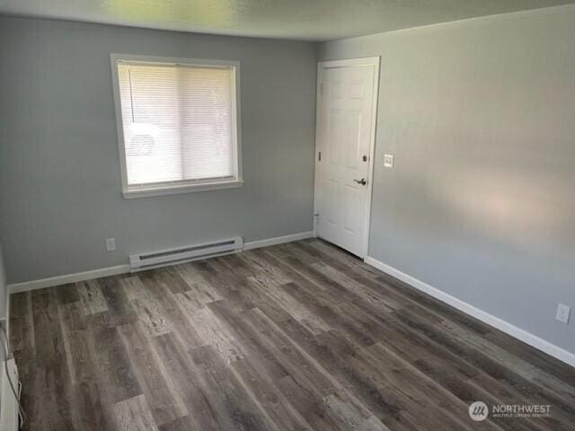 unfurnished room featuring dark wood-style floors, a baseboard radiator, and baseboards