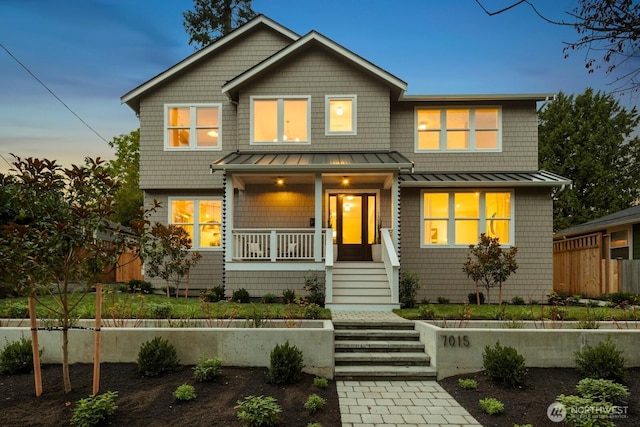 craftsman-style home with a porch, a standing seam roof, fence, and stairway