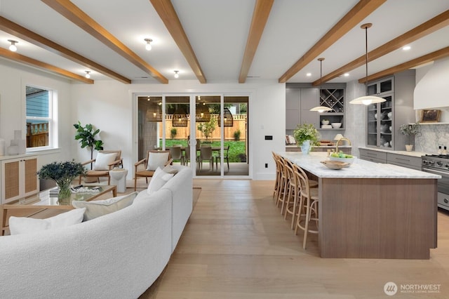 kitchen featuring a kitchen island with sink, stainless steel range, gray cabinets, and a breakfast bar area