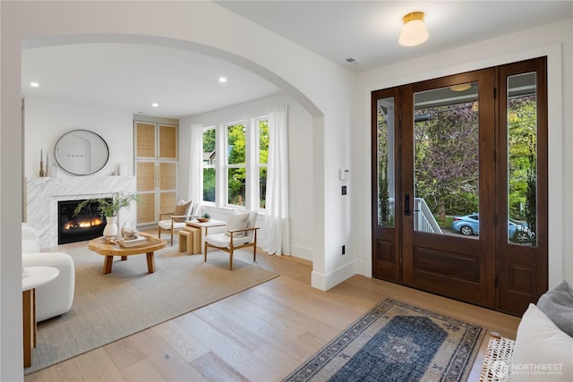 foyer with arched walkways, a fireplace, wood finished floors, and recessed lighting