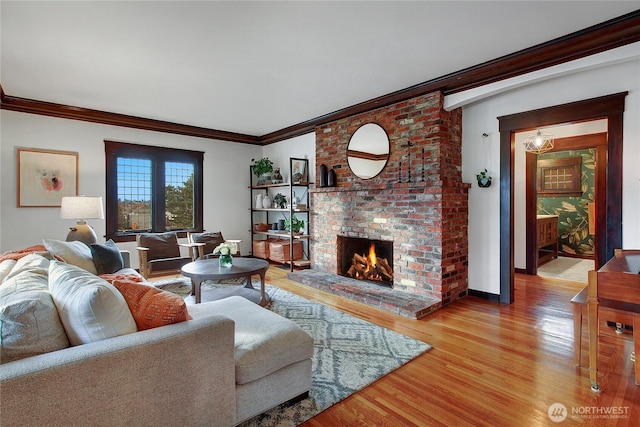 living area with light wood finished floors, a fireplace, baseboards, and crown molding