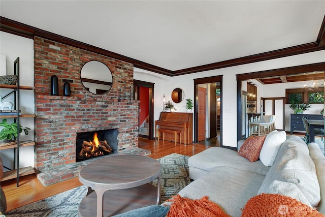 living room featuring ornamental molding, a brick fireplace, and wood finished floors