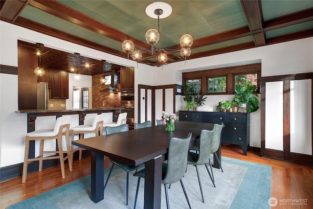 dining room featuring a notable chandelier, light wood finished floors, beamed ceiling, and baseboards