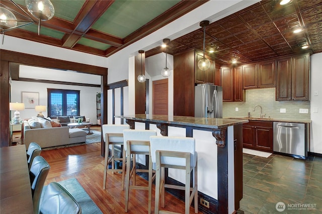 kitchen with pendant lighting, a breakfast bar area, stainless steel appliances, open floor plan, and a sink