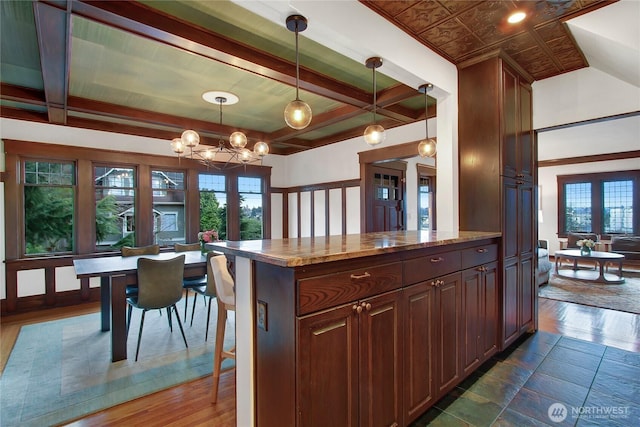 kitchen with a chandelier, light stone counters, a breakfast bar area, hanging light fixtures, and a center island