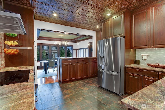 kitchen with black electric cooktop, range hood, tasteful backsplash, stainless steel fridge, and an ornate ceiling