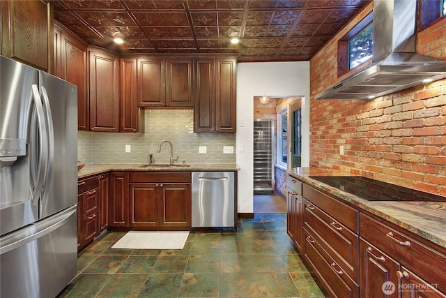 kitchen with stainless steel appliances, wall chimney range hood, a sink, and an ornate ceiling