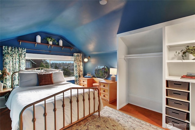 bedroom with vaulted ceiling and wood finished floors