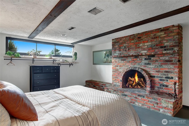 bedroom with a textured ceiling, a fireplace, and visible vents