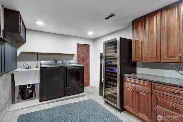 laundry room featuring wine cooler, washing machine and clothes dryer, visible vents, cabinet space, and a sink