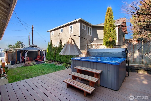 deck with a hot tub, fence, a lawn, and a gazebo