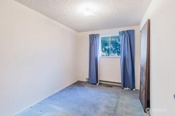 carpeted spare room with a textured ceiling